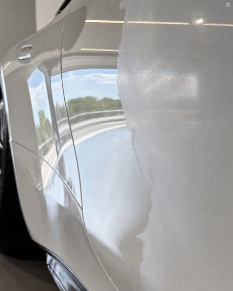Polierkante an der weißen Flanke des Mercedes-AMG GT 63 nach dem SONAX SchaumPad hart: klare Spiegelung neben mattem Lack.
