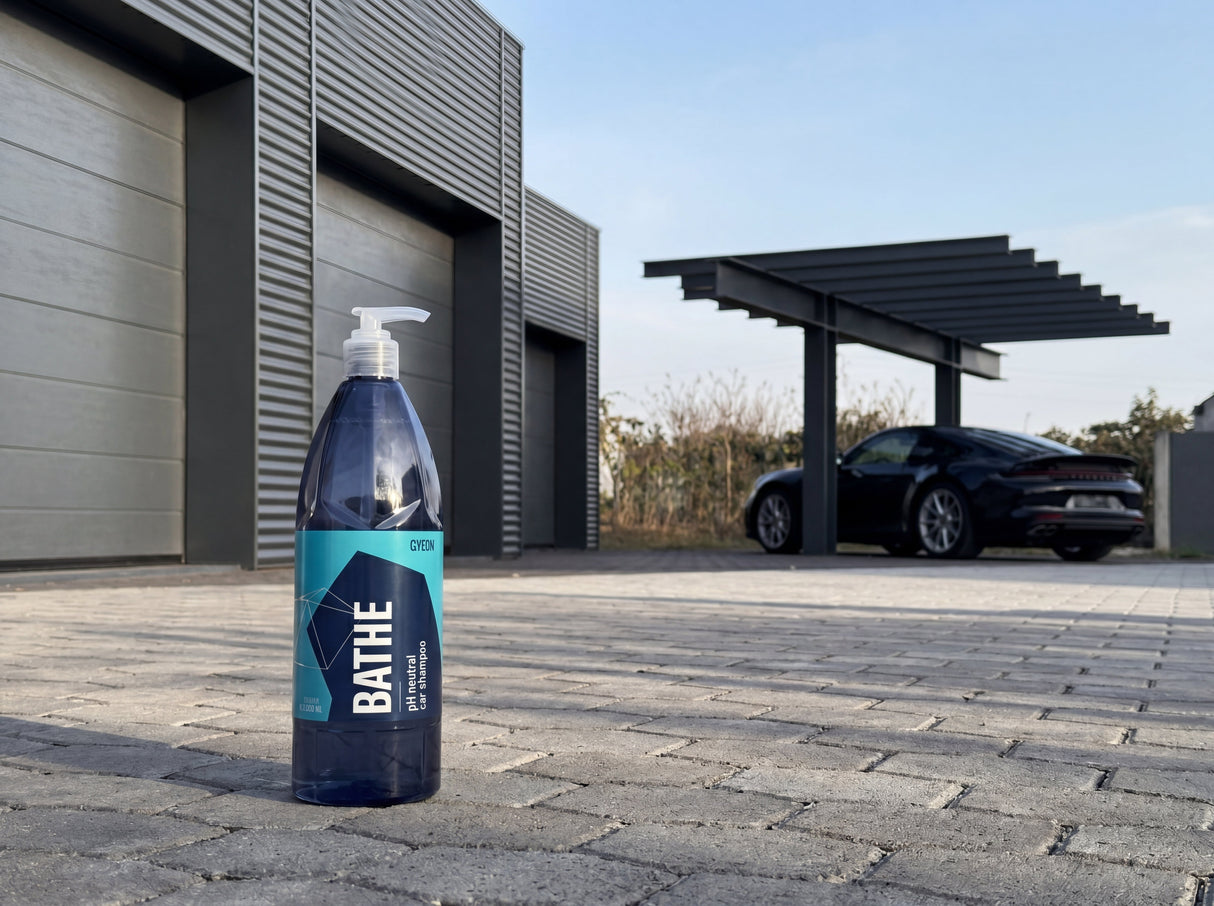 GYEON Q²M Bathe Autoshampoo Flasche auf Paving Stone vor Porsche 911