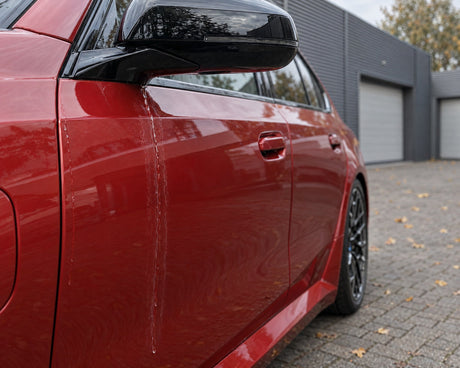 Detailing1 asciugare l'auto — l'acqua che cola dallo specchietto lascia macchie di calcare sulla portiera di una BMW M5 rossa