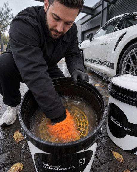 Meguiars Hybrid Wash Mitt: Daniel reibt den Waschhandschuh im Spüleimer über das gelbe Grit Guard Schmutzsieb
